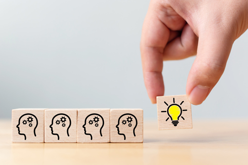 Concept creative idea and innovation. Hand picked wooden cube block with head human symbol and light bulb icon Concept creative idea and innovation. Hand picked wooden cube block with head human symbol and light bulb icon